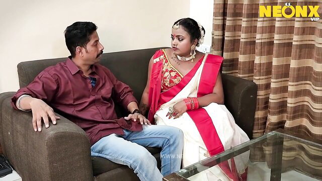 Indian wife in red saree sits with man on couch in steamy adult scene