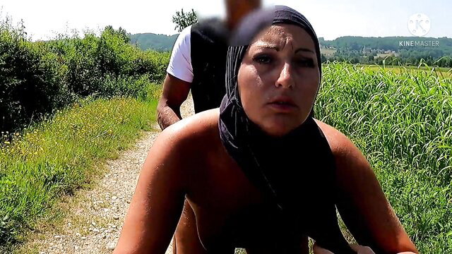 Nude Muslim woman in hijab outdoors with man behind, explicit tease