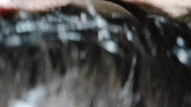 Closeup of woman's wet black hair and face in intense adult action