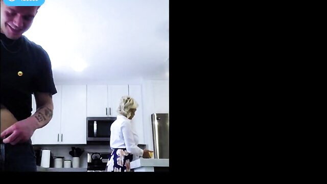 Young guy in cap grabs tanned milf's waist in kitchen fuck scene