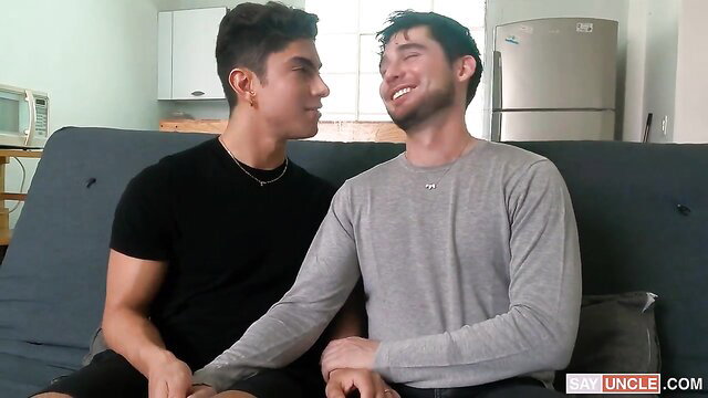 Two handsome Latino guys cuddling intimately on couch in Honeymoon Preview