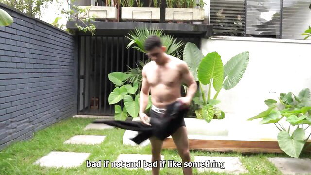 Muscular Asian man in black underwear outdoors in tropical yard