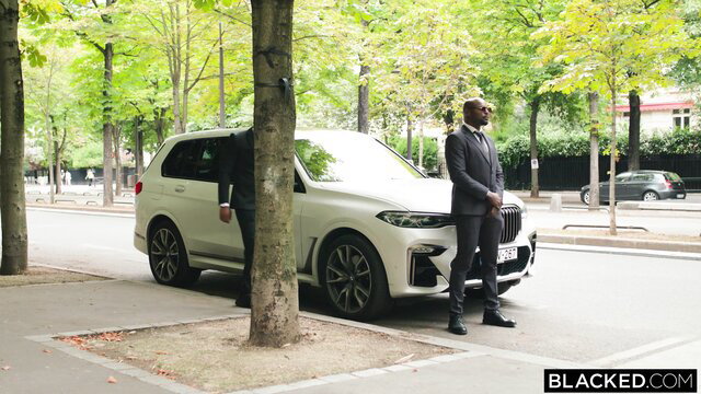 Ashby Winter with black suited man by white BMW X7 in Paris street