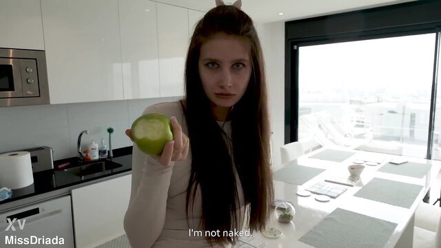 Urakadaki holds green apple in kitchen, long hair, pale skin, clothed tease