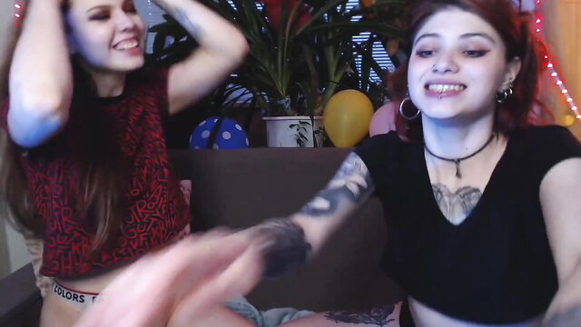 Two cute tattooed lesbians smiling playfully in skimpy tops and shorts