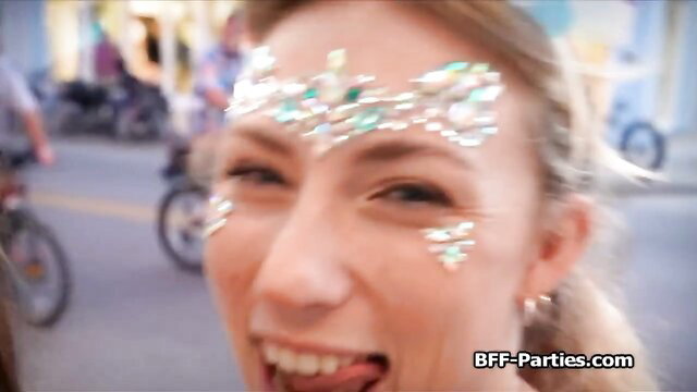 Blonde party chick with glitter face paint smiling at camera