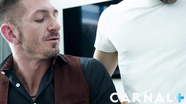 Two hot men in tight shirts embrace intimately in Carnal+ gay scene