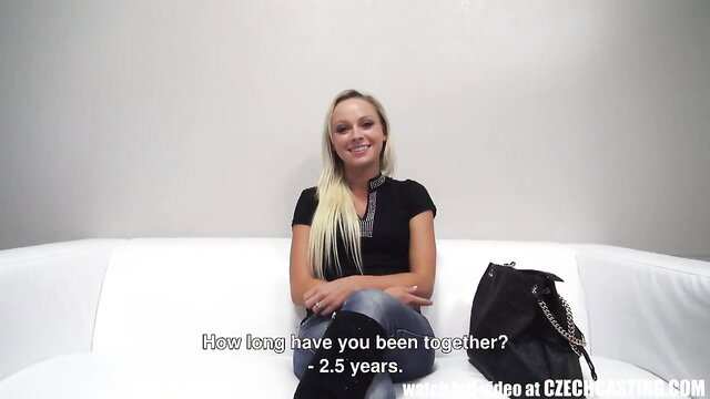 Smiling Czech blonde in tight top and jeans on couch, 2.5 years text