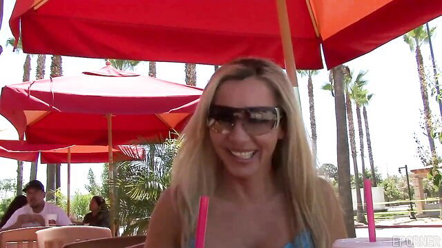 Blonde bombshell in bikini sips drinks at beachside pool bar