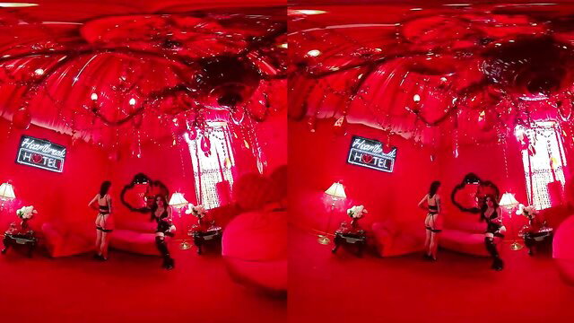 Two lingerie-clad shemales embracing in red-lit VR motel room