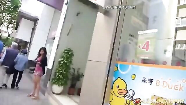 Asian beauty in skimpy pink minidress and flip flops outside shop