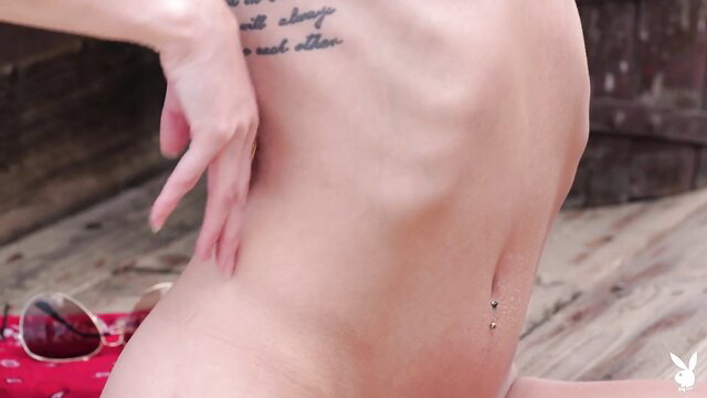 Slim nude tattooed babe teases with navel piercing outdoors