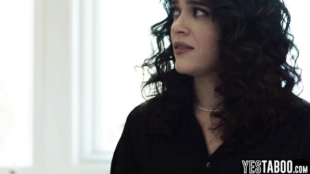 Victoria Voxxx in black top, curly black hair, seductive gaze