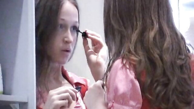 Brunette amateur applying mascara in mirror, showing off skills