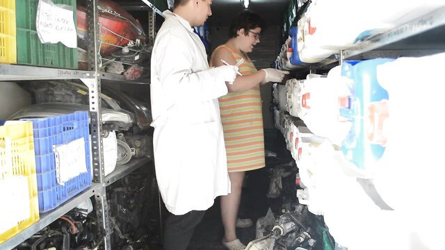 Fat mechanic woman in striped dress bends for tools in workshop
