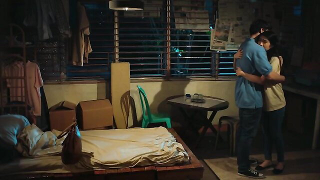 Clothed Asian couple embracing intimately in bedroom