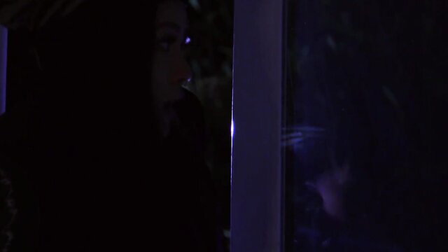 Rae Lil Black tied up against glass, intense gaze in Brazzers scene