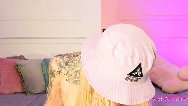 Blonde tattooed model in pink bucket hat on bed, sneak peek hairy anal dildo tail