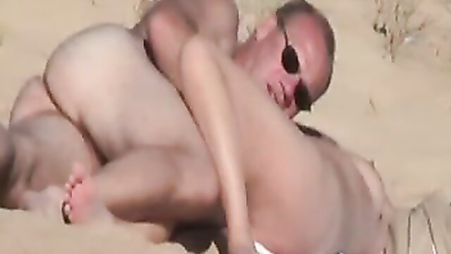 Nudist couple horny embrace on beach, nude bodies intertwined