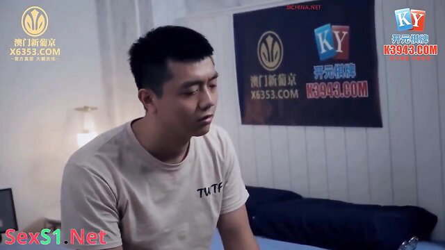 Asian man in TVF tee sits pensively on bed in steamy threesome preview