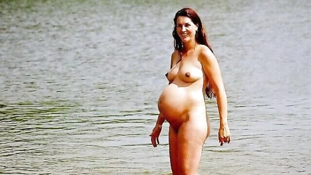 Nude pregnant redhead with big tits standing in water, showing bump