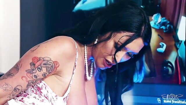 TS Bella Joie in sexy dress with tattoos and pearls, seductive gaze