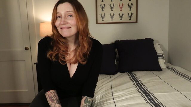 Bettie Bondage in black V-neck top, red hair, tattoos, bedroom POV tease