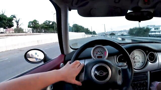 POV female driver gripping wheel in Mini Cooper on highway
