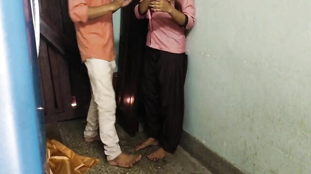 Indian schoolgirl in pink top black pants barefoot with man by door