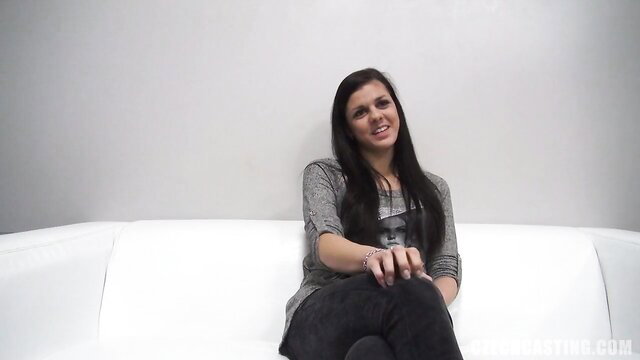 Brunette beauty smiling on couch at casting, ready to ride