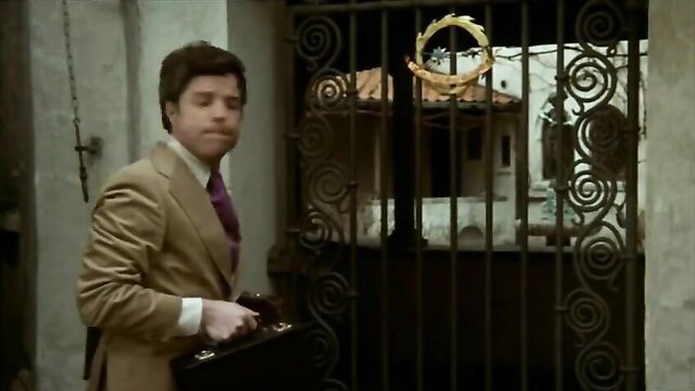 Man in tan suit with briefcase at ornate gate in In the Sign of the Virgin movie thumbnail