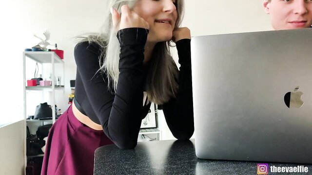 Eva Elfie smiling at camera in black top and pink skirt next to boyfriend