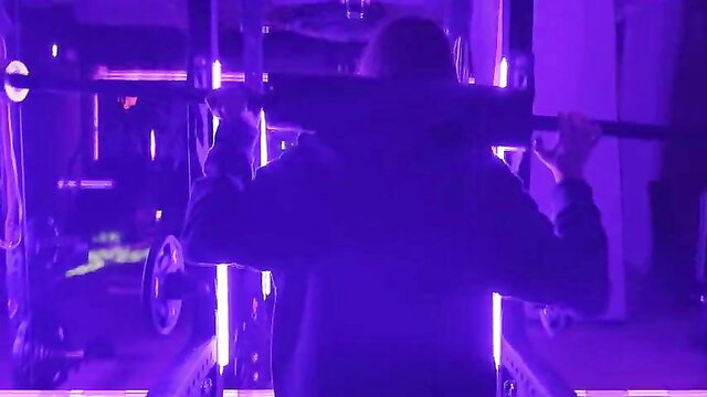 Muscular hooded man deadlifting in neon gym, scarlettandc style