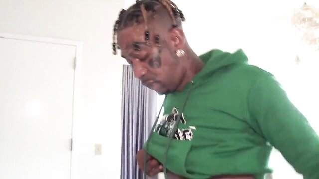 Tattooed black man in green hoodie grabs crotch in lustful thumbnail