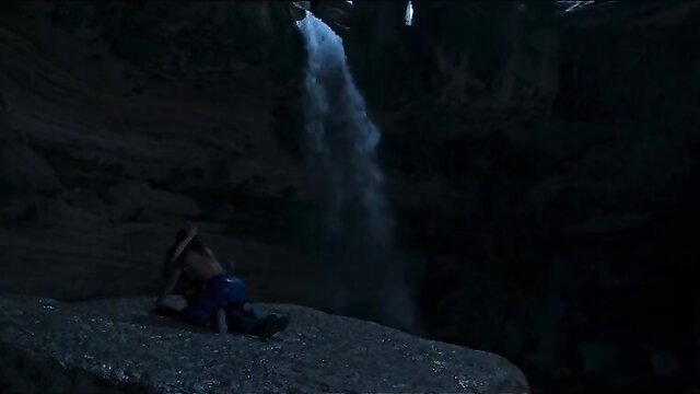 Woman in hat sits by cave waterfall, nude tits from Welcome to Eden