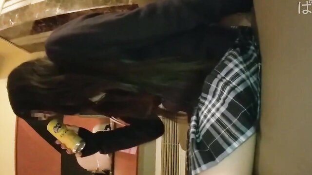 Priva bends over in plaid skirt, holding yellow can, upskirt tease