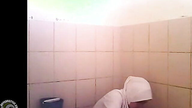 Arab woman squatting to pee in public toilet, hijab on