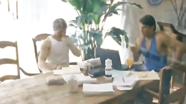 Two muscular men in tank tops at table in Passion Cove Deep Desires