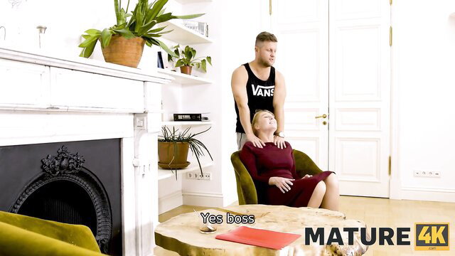 Mature boss in red dress gets neck massage from bearded stud in tank top