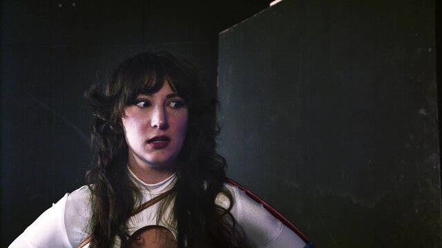 Fringe-haired brunette in sheer white top with orange straps, seductive gaze