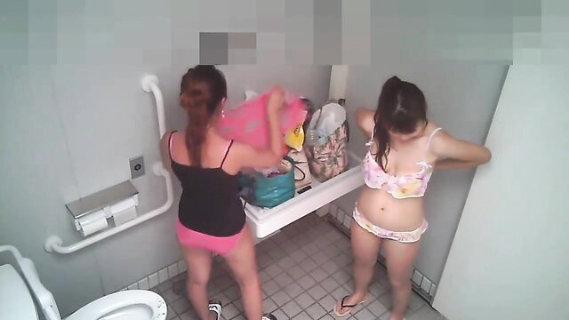 Two Asian girls changing clothes in beach toilet, bikinis and panties