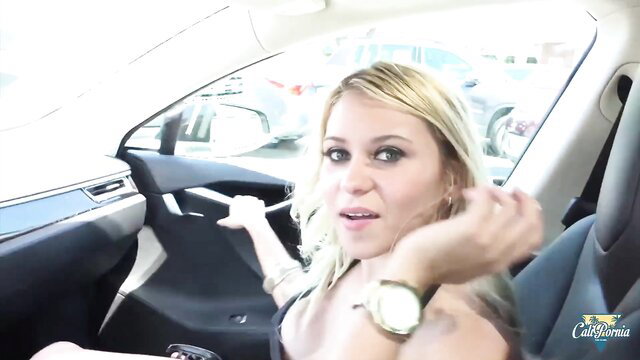 Blonde babe Marsha May in car, low-cut top showing cleavage