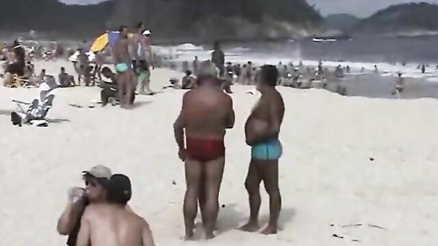 Old white and black men in speedos chatting on sunny beach