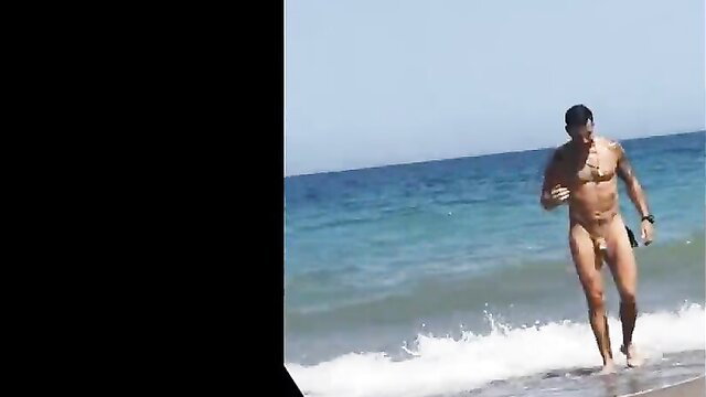 Hot nude Latino guy walking naked on gay beach by ocean waves