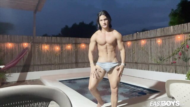Muscular Latino twink in tight briefs poses by pool at night