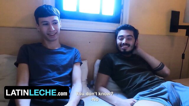 Two men in a hotel room, smiling, with one lying down