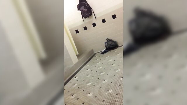 Blurry shower room with black backpacks on floor and hook post-shower