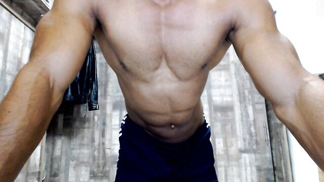 Muscular Indian stud flexing ripped abs and arms in tight shorts