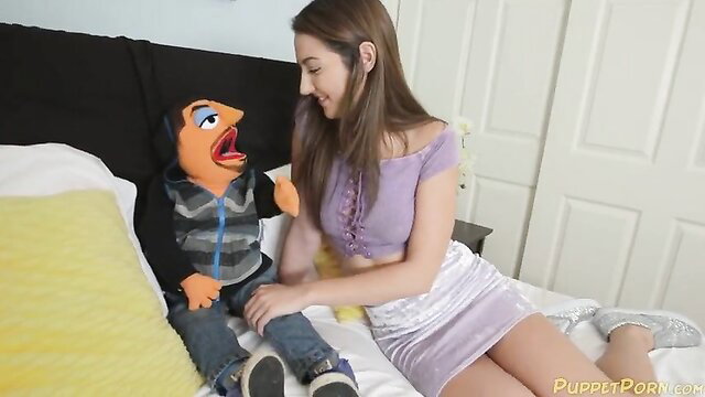 Lily Adams in skimpy purple top and skirt with puppet on bed