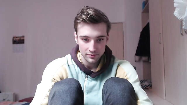 Handsome young twink in hoodie sits knees up in gay amateur video thumbnail